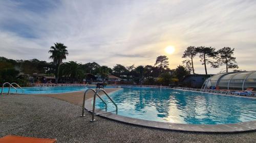 einen Pool in einem Resort mit Sonnenuntergang in der Unterkunft Joli Bungalow Cap Ferret Camping les Viviers in Lège-Cap-Ferret