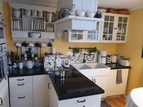 uma cozinha com armários brancos e bancadas pretas em Haus Nadine em Lübeck