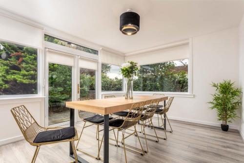 a dining room with a table and chairs and windows at Cuthbert House in Prestwick