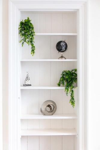 a white book shelf with two plants on it at Cuthbert House - Donnini Apartments in Prestwick