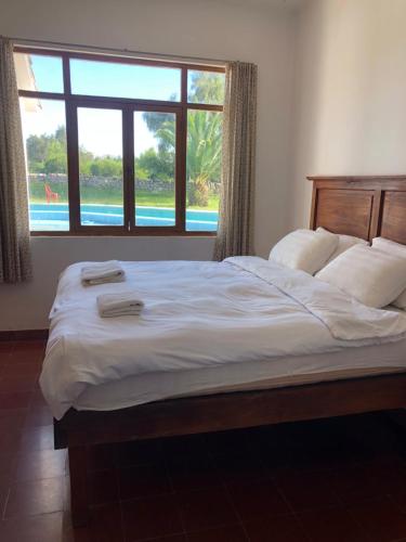 a bedroom with a large bed with a large window at Poneloya in Tarija