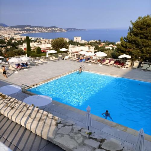 une grande piscine avec une personne dans l'eau dans l'établissement EXCEPTIONNEL 4 pieces vue panoramique baie des anges proche plage, à Nice