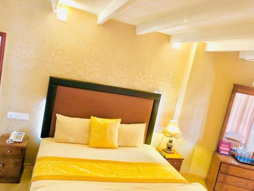 1 dormitorio con 1 cama grande con almohada amarilla en Moon plain resort, en Nuwara Eliya