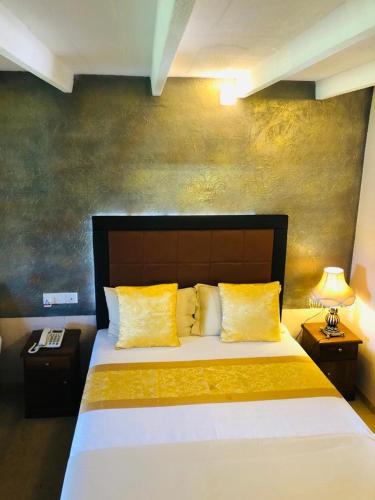 1 dormitorio con 1 cama grande con almohadas amarillas en Moon plain resort, en Nuwara Eliya