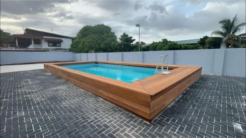 uma piscina com uma varanda de madeira e um estore de estandarte em Paradijs in Paramaribo em Paramaribo