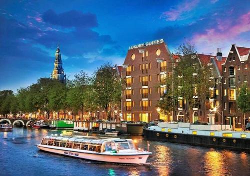 a boat in a river in front of a building at Luxury Suites Amsterdam in Amsterdam