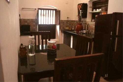 a kitchen with a table and a black refrigerator at UDUPI HERITAGE INN in Udupi