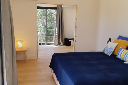 een slaapkamer met een blauw bed en een glazen schuifdeur bij Maison contemporaine au Paradou. Piscine. in Paradou