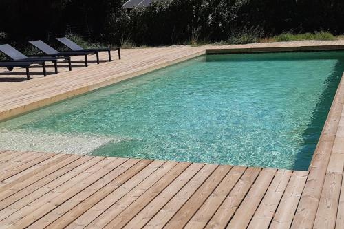 une piscine avec des chaises et une terrasse en bois dans l'établissement Maison contemporaine au Paradou. Piscine., à Paradou