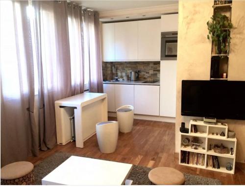 une cuisine avec des armoires blanches et une table dans une pièce dans l'établissement 2 pièces lumineux et calme à Paris, à Paris