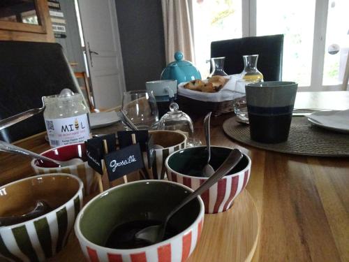 a table with bowls and spoons on a wooden table at La Méridienne - Chambres d'hôtes in Venterol