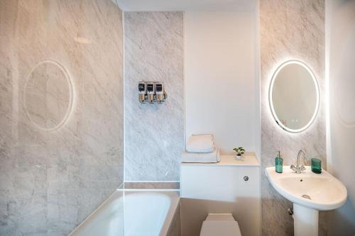 W łazience znajduje się wanna, umywalka i lustro. w obiekcie Reading 2-Bed Apartment & Parking w mieście Caversham