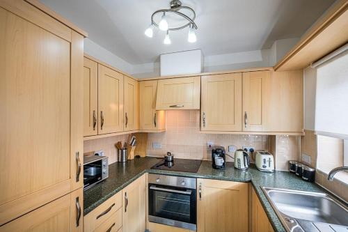 a kitchen with wooden cabinets and a sink at Reading 2-Bed Apartment & Parking in Reading