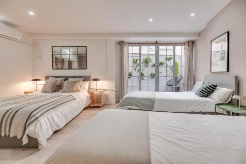 a white bedroom with two beds and a window at Victoria 16 Premium by Nagoa Homes in Málaga