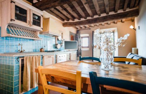 a kitchen with a wooden table with a vase of flowers at Rifugium in Greve in Chianti