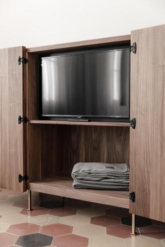 a flat screen tv on a wooden entertainment center at LA CASA DI LAURA in Valdobbiadene