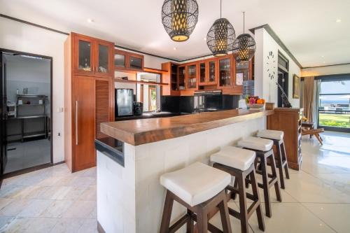a kitchen with a large counter with stools at BougainVilla - Oceanfront villa with Cook, ideal for Weddings and Events in Keramas