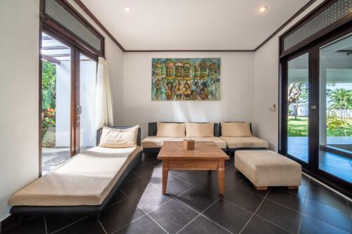 a living room with a couch and a table at BougainVilla - Oceanfront villa with Cook, ideal for Weddings and Events in Keramas