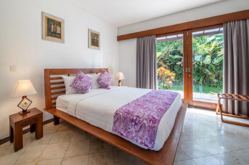 a bedroom with a large bed and a large window at BougainVilla - Oceanfront villa with Cook, ideal for Weddings and Events in Keramas