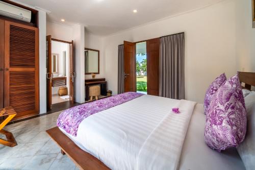 a bedroom with a large bed with purple pillows at BougainVilla - Oceanfront villa with Cook, ideal for Weddings and Events in Keramas