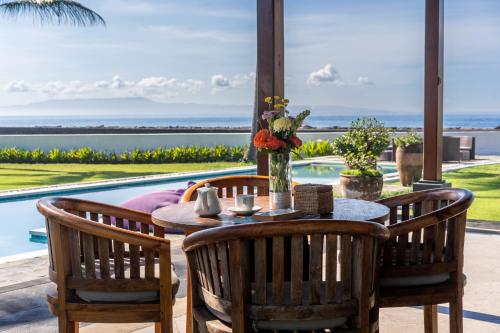 a patio with a table and chairs and a pool at BougainVilla - Oceanfront villa with Cook, ideal for Weddings and Events in Keramas