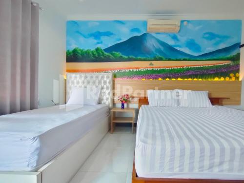 1 dormitorio con 2 camas y un cuadro en la pared en Joy Homestay Near UMJ Jember Mitra RedDoorz en Jember