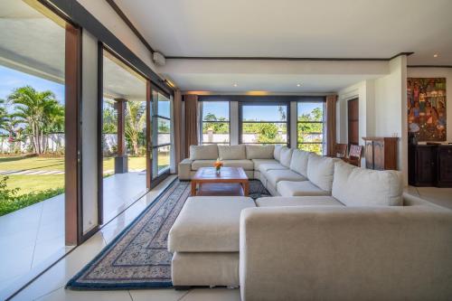 a living room with a couch and a table at BougainVilla - Oceanfront villa with Cook, ideal for Weddings and Events in Keramas