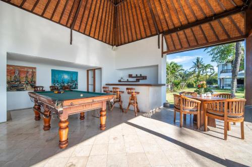 a pool table in a room with a table and chairs at BougainVilla - Oceanfront villa with Cook, ideal for Weddings and Events in Keramas