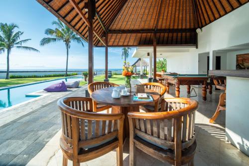 an outdoor dining area with a table and a pool at BougainVilla - Oceanfront villa with Cook, ideal for Weddings and Events in Keramas