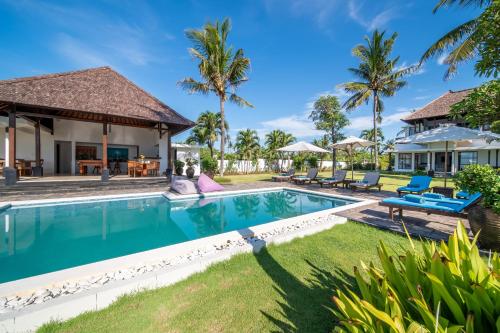 a swimming pool in front of a house with palm trees at BougainVilla - Oceanfront villa with Cook, ideal for Weddings and Events in Keramas