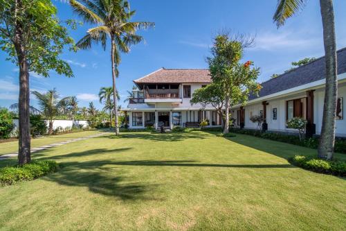 a house with palm trees in front of a yard at BougainVilla - Oceanfront villa with Cook, ideal for Weddings and Events in Keramas