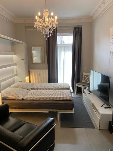 Schlafzimmer mit einem Bett, einem TV und einem Kronleuchter in der Unterkunft Apartment Glasower 31 in Berlin