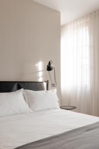 a bedroom with a white bed with a lamp and a window at LA CASA DI LAURA in Valdobbiadene