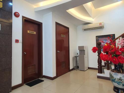 a hallway with two doors and a vase of flowers at Capital O 90939 Sandakan Central Hotel in Sandakan