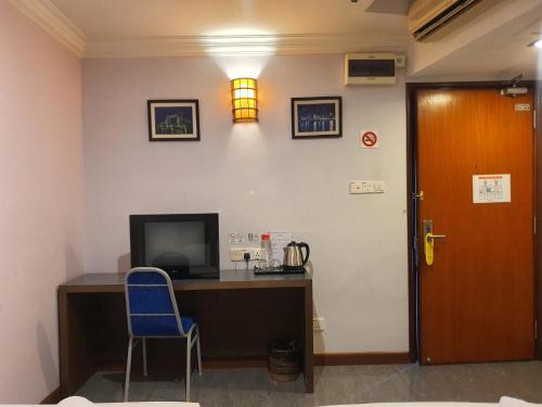 a room with a desk with a tv and a blue chair at Capital O 90939 Sandakan Central Hotel in Sandakan