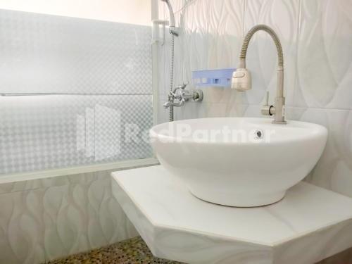 La salle de bains est pourvue d'un lavabo blanc et d'un robinet. dans l'établissement Joy Homestay Near UMJ Jember Mitra RedDoorz, à Jember