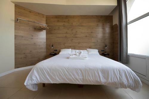 Schlafzimmer mit einem großen weißen Bett und Holzwänden in der Unterkunft Apartamento familiar exterior en la costa de Zarautz - Oasis Palm in Zarautz