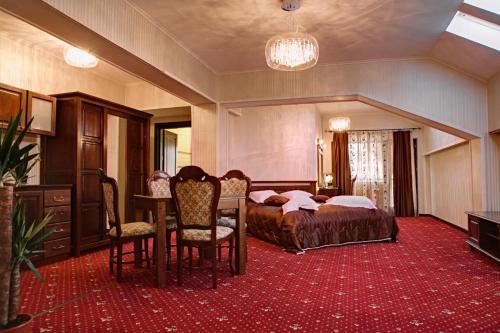 Hotel Bistrita في دوراو: غرفة نوم بسرير وطاولة وكراسي