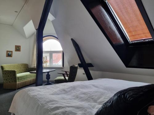 a bedroom with a bed and a window and a chair at Mikkelborg Kro in Rødding