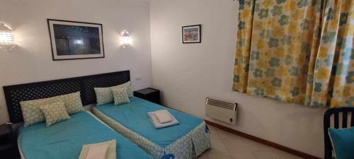 um pequeno quarto com uma cama com uma colcha azul em Albufeira INN - Casa da Peneda - Bellavista T1 em Albufeira