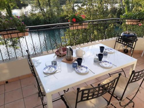 une table blanche et des chaises sur un balcon dans l'établissement Ô Pied Dans l'O, villa pieds dans l'eau à proximité du Lac du Bourget / Aix les Bains, à Chanaz