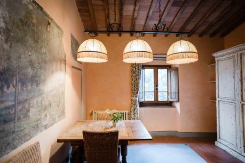 a dining room with a wooden table and chandeliers at Rifugium in Greve in Chianti
