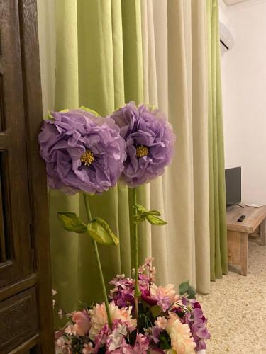a vase with purple flowers in front of a curtain at Casa Graziusa in Palermo