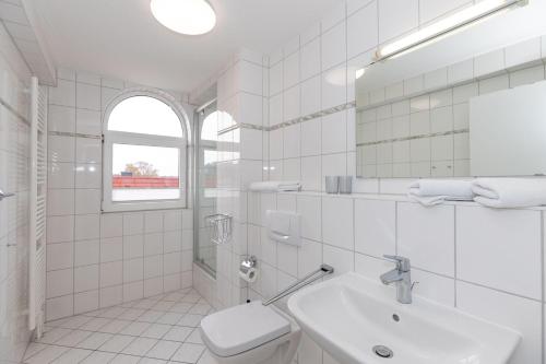a white bathroom with a sink and a toilet at Strandschloesschen-I-WE-21-684 in Kühlungsborn