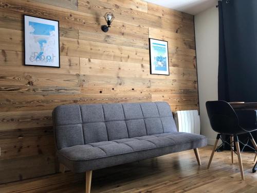 ein Sofa in einem Zimmer mit einer Holzwand in der Unterkunft Lou Bigourdan in Cauterets