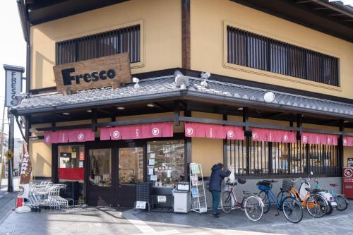 a person standing outside of a store with bikes parked outside at Guest House Goettingen in Kyoto