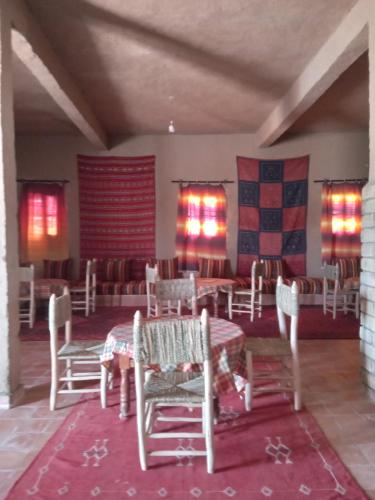 una sala da pranzo con tavolo e sedie in una stanza di Hostel la palmeraie merzouga a Merzouga
