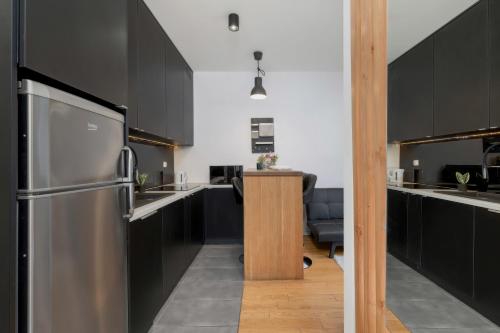 a kitchen with black cabinets and a stainless steel refrigerator at Cosy Ariańska Apartment for 3 in Cracow Center by Renters in Krakow