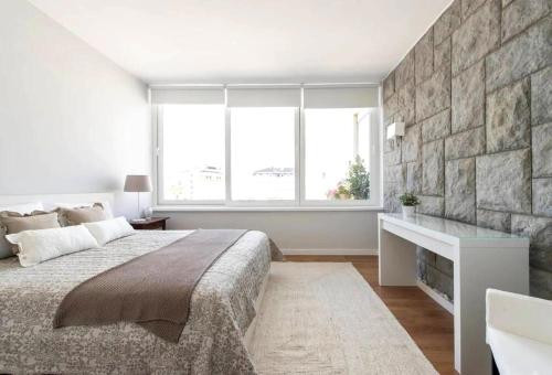 una camera con un grande letto e un muro di pietra di Elegant and bright apartment in Estoril a Estoril