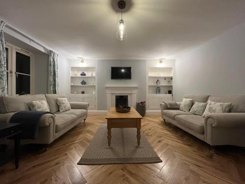 a living room with two couches and a fireplace at Luxury farmhouse in secluded Cotswold valley in Uley